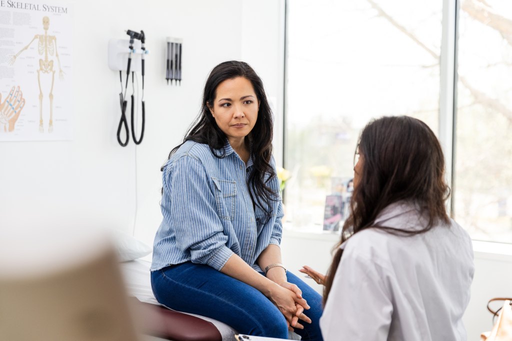 woman sitting in doctor's office talking to physician