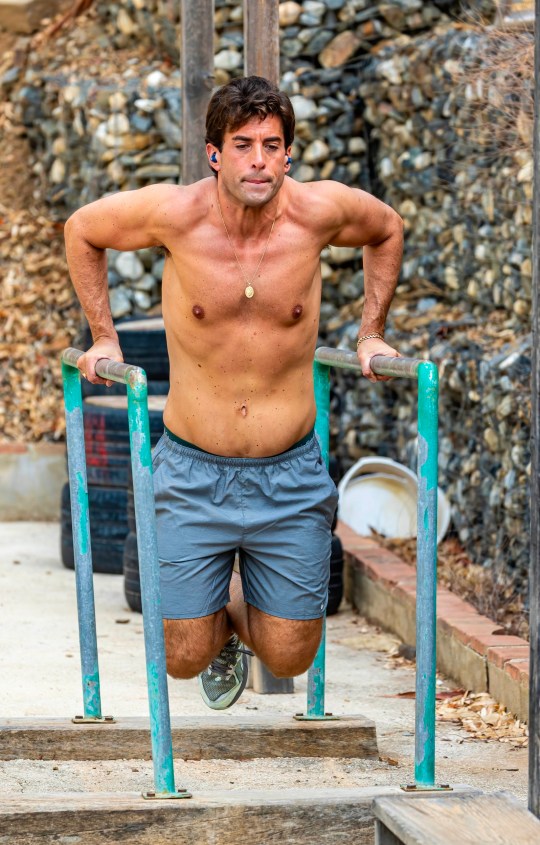 James Argent wearing blue shorts and using bars to workout
