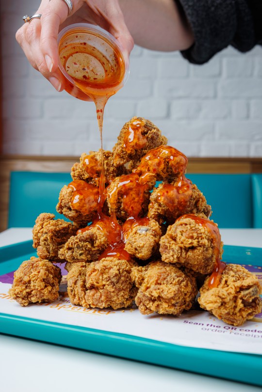 Hot Honey sauce being drizzled on chicken wings at Popeyes