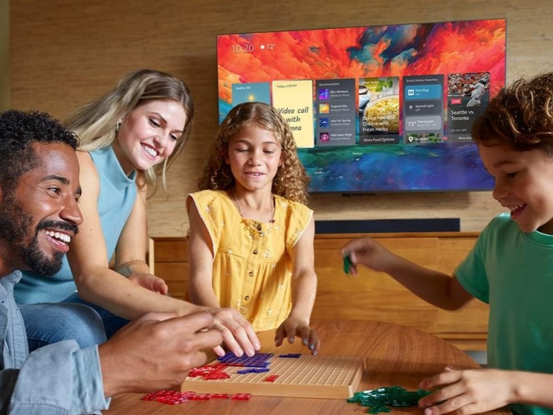 Amazon Fire TV Omni QLED TV on wall behind family