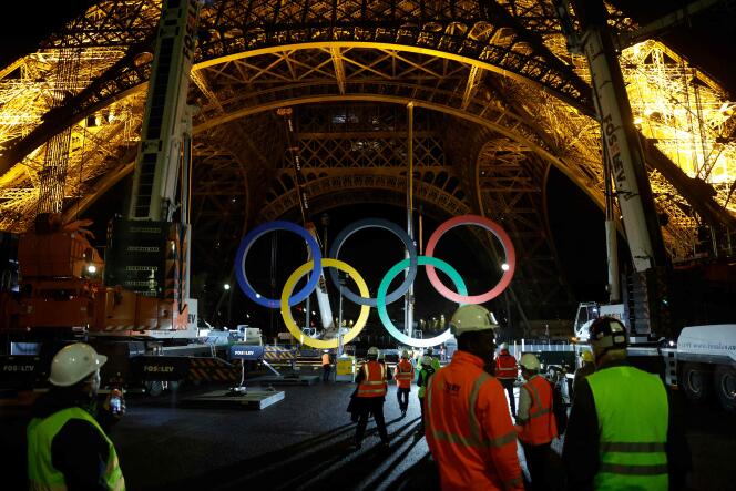 Workers watch cranes remove the Olympic rings from the Eiffel Tower, in Paris, on September 27, 2024.