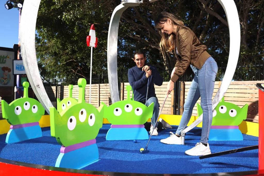 woman playing pixar mini golf putt with toy story theme