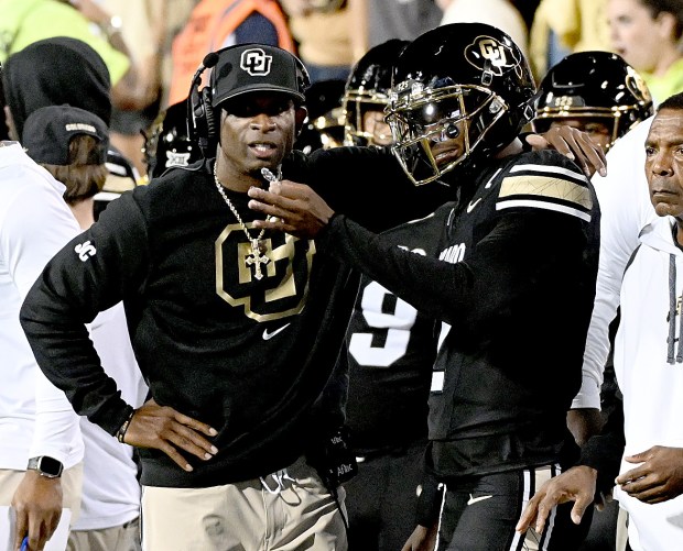 Colorado head football coach Deion Sanders talks to his son...