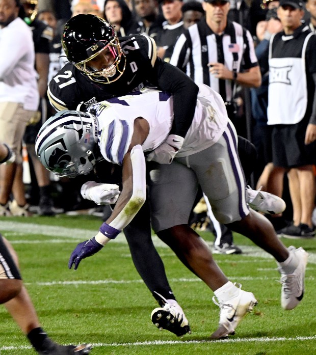 Colorado safety Shilo Sanders, left, tries to tackle Kansas State...