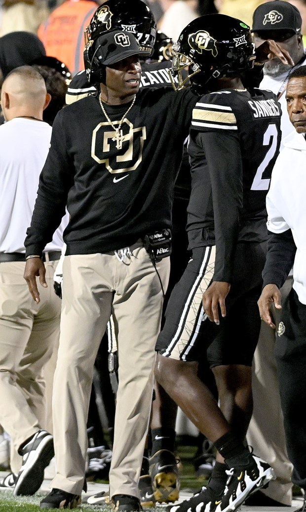 Colorado head football coach Deion Sanders talks to his son...