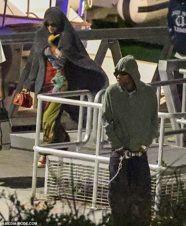 Travis, whose real name is Jacques Bermon Webster II, was joined by an entourage of stunning ladies - and a mystery woman who went to great lengths to conceal her identity (pictured left)
