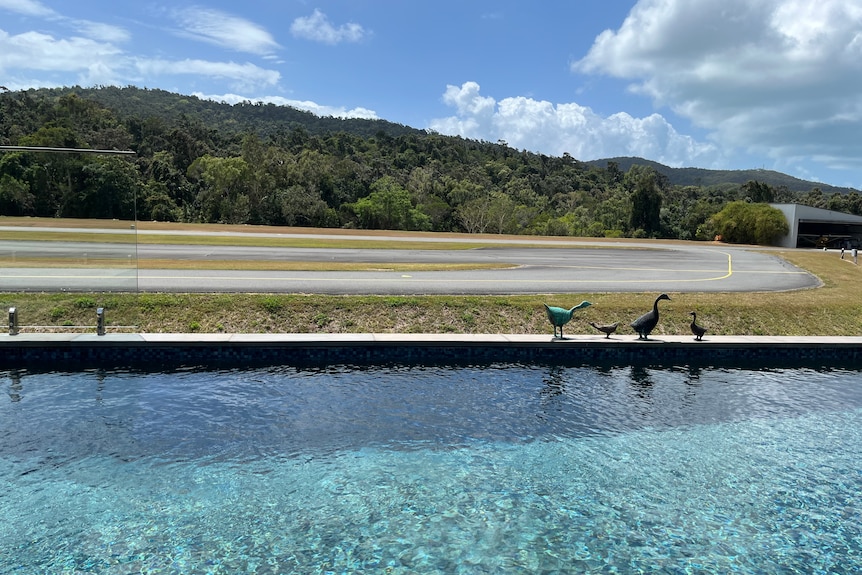A swimming pool in front of an airport runway 