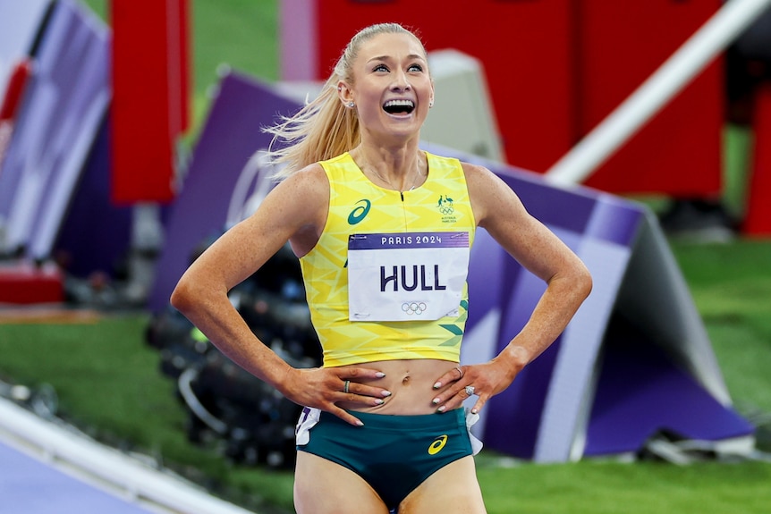 A woman in athletics attire stands with her hands on her hips